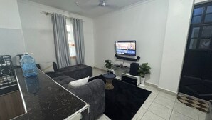 Una sala de estar moderna con una mesa de centro de mármol negro, un sofá gris, un televisor de pantalla plana montado en la pared y un ventilador de techo.