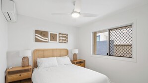 A bedroom with a bed, nightstands, a ceiling fan, and artwork on the wall. - Thirty-Nine Albatross (Apartment 3) (Mermaid Beach)