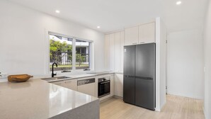 A modern kitchen with a large island, built-in oven, and a stainless steel refrigerator. - Thirty-Nine Albatross (Apartment 3) (Mermaid Beach)