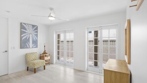 A spacious room with a ceiling fan, a bed with a patterned cover, a small table with a lamp, and a wooden cabinet. - Thirty-Nine Albatross (Apartment 3) (Mermaid Beach)