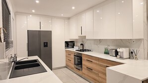 Eine moderne Küche mit weißen Schränken, einem Edelstahlkühlschrank, einem Gasherd und einem eingebauten Backofen.