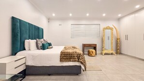 Ein modernes Schlafzimmer mit Bett, Nachttisch, Kleiderschrank und einem dekorativen Spiegel.