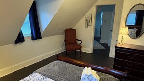 Une chambre à coucher avec un lit, une chaise, une commode et un miroir.