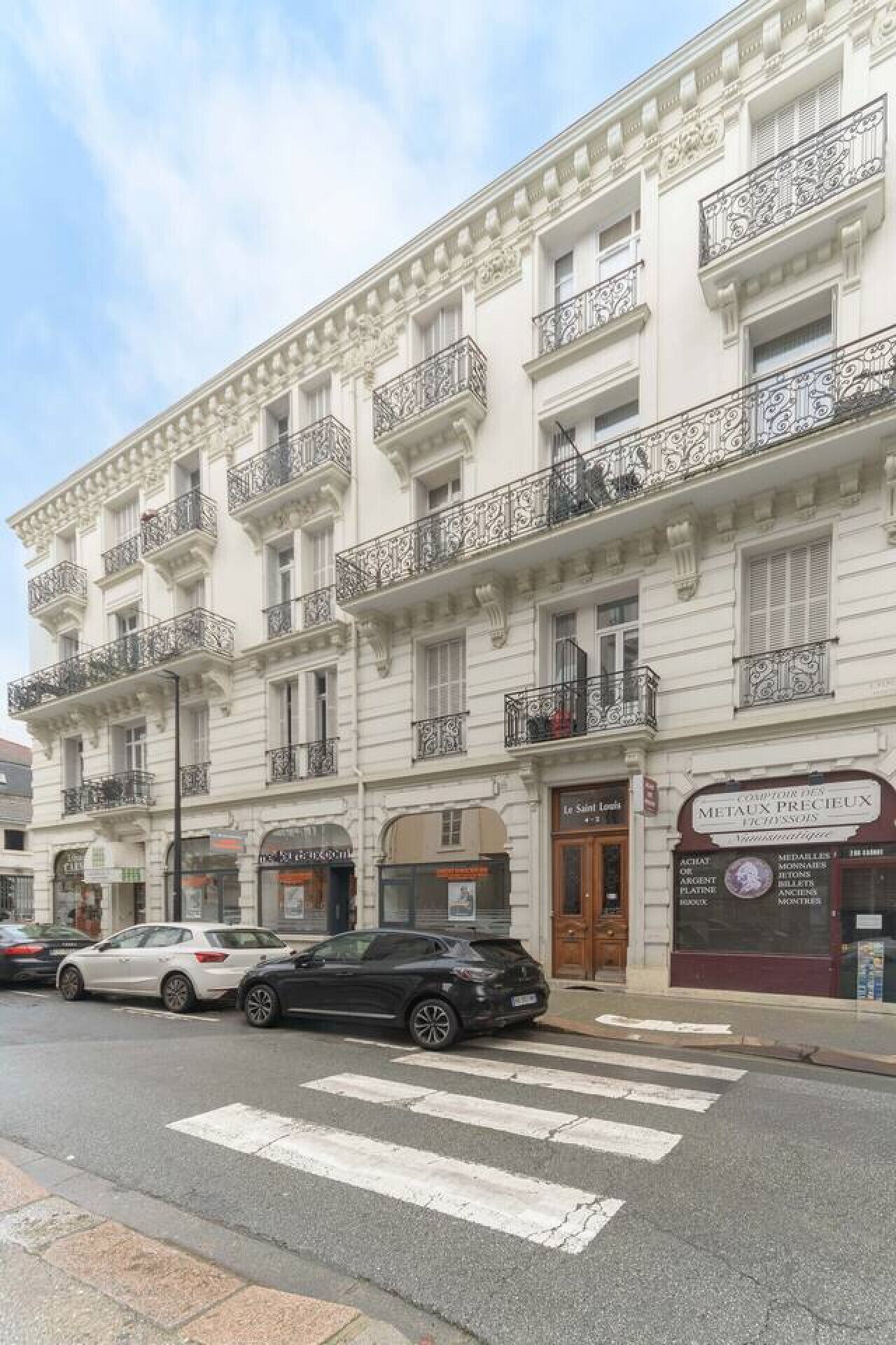 A multi-story building with ornate balconies and a storefront with signage.