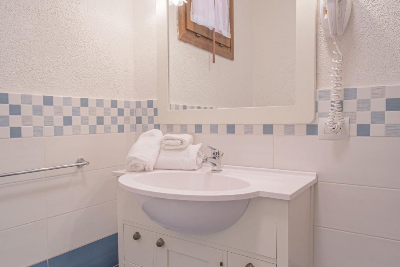 A bathroom with a white sink, a towel rack, and a mirror.