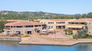 Ein Hotel an der Küste mit Pool, Sitzgelegenheiten im Freien und Meerblick.