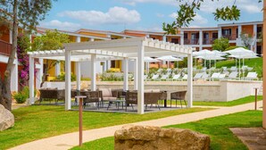 Ein HotelInnenhof mit Außenmöbeln, einem Pool und einem großen Felsen im Vordergrund.