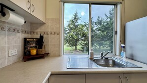 Una cocina con ventana, un fregadero y un libro titulado 'Women's Weekly Slow Cook'.
