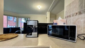 Una cocina moderna con cafetera, microondas y tabla de madera en la encimera.