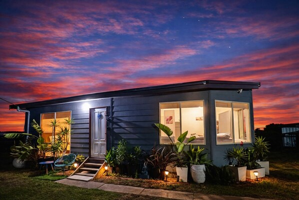 A modern house with a well-lit entrance, large windows, and a small porch with outdoor seating.