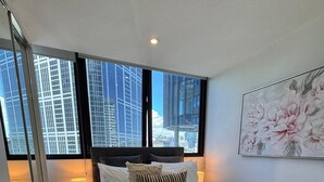 Quarto moderno com cama grande, vista para a cidade e uma obra de arte floral na parede.