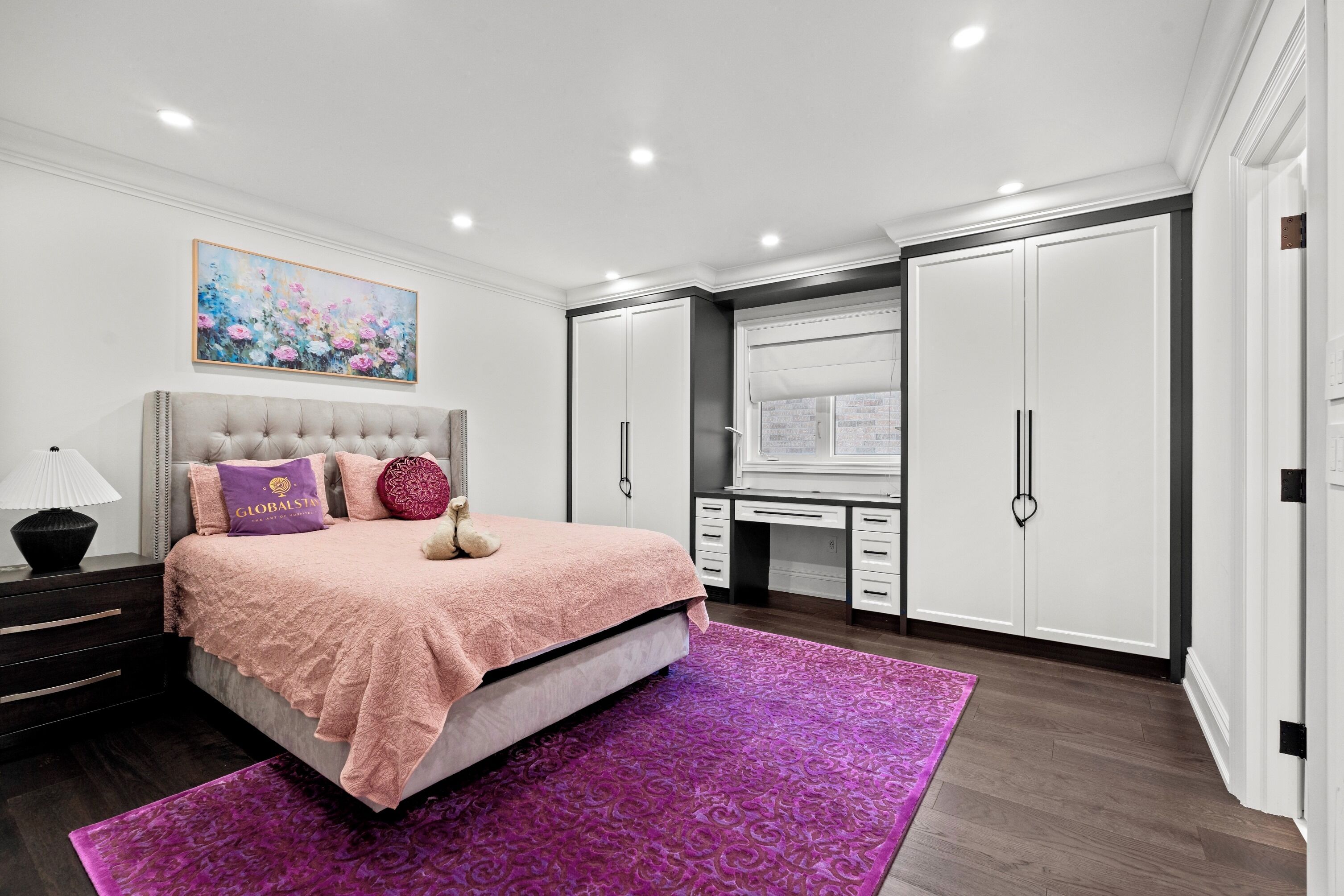 A bedroom with a bed, a desk, and a wardrobe.