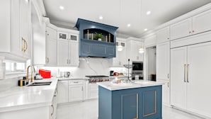 Une cuisine moderne avec des meubles blancs, un mur d’accent bleu et des appareils électroménagers en acier inoxydable.