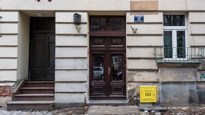 A building with a dark wooden double door, a visible number 12 sign, and a yellow gas meter. - Apartamenty Sun & Snow Sunshine Loft (Kraków)