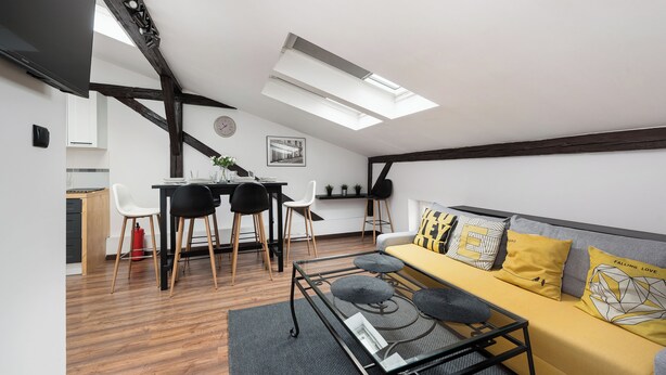 A modern living room with a sofa, coffee table, and dining area. - Apartamenty Sun & Snow Sunshine Loft (Kraków)