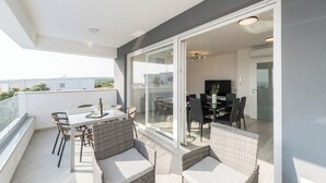 Un balcon équipé d’une table et de chaises, d’un canapé et d’une porte-fenêtre coulissante donnant sur un espace de repas intérieur.