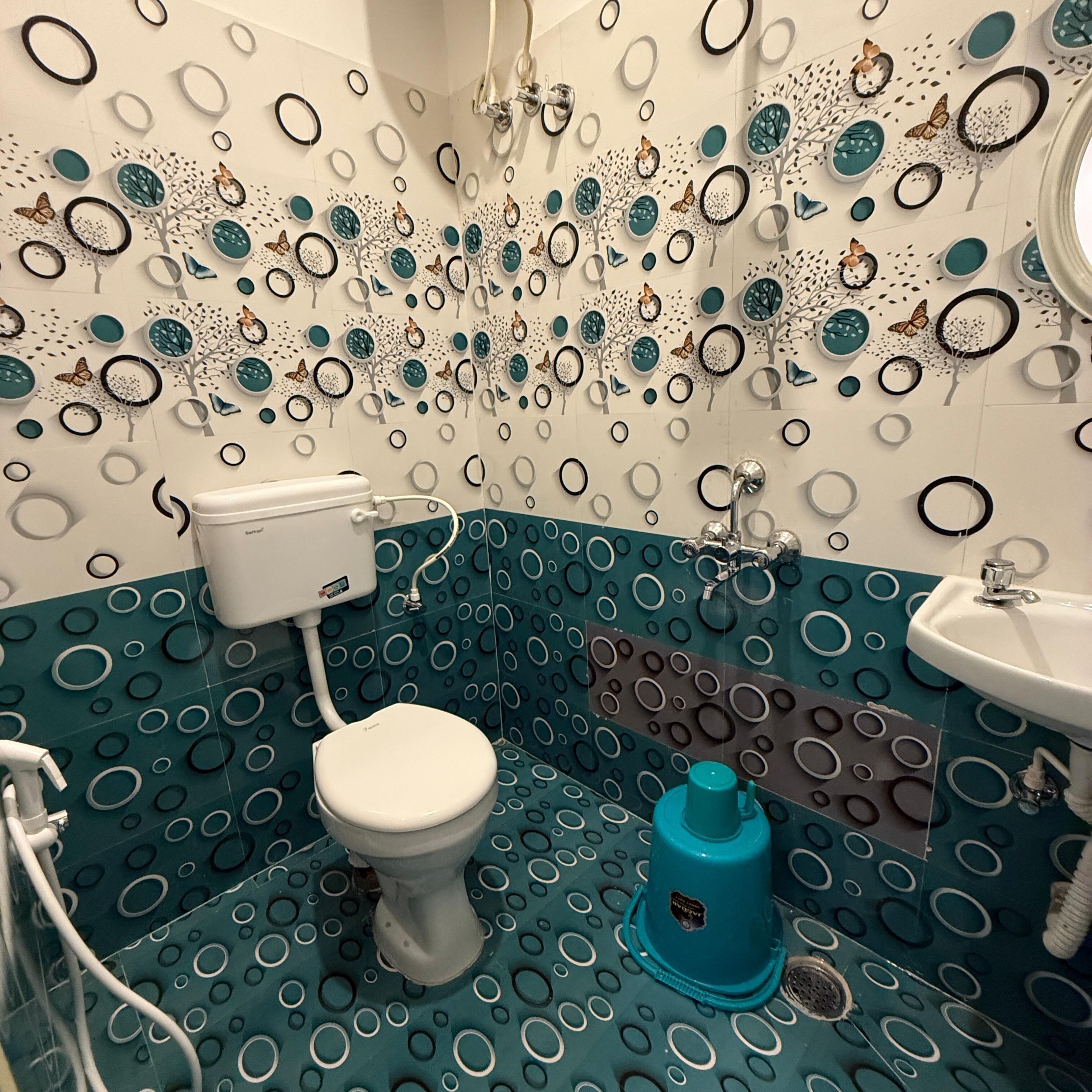 A bathroom with a toilet, sink, and shower area. The walls are decorated with circular patterns and some trees and butterflies.