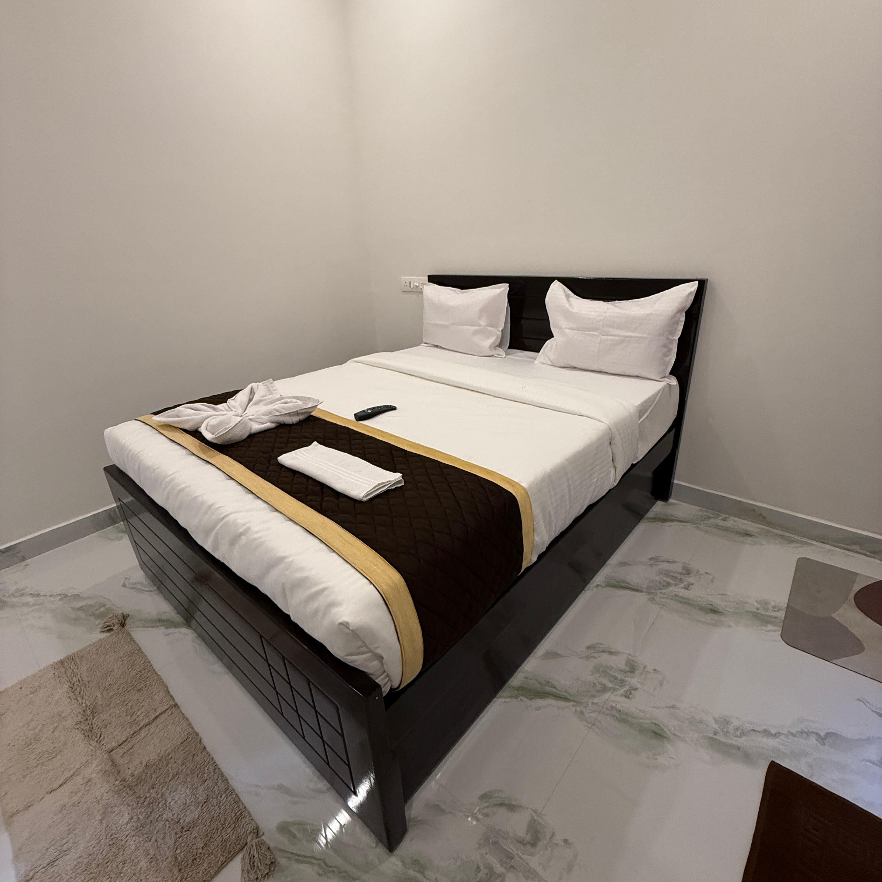 A neatly made bed with a black headboard, white bedding, and a brown accent.