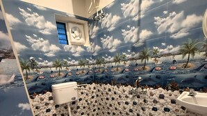 Ein Badezimmer mit tropischem Wandgemälde, einer Toilette und einem Waschbecken.