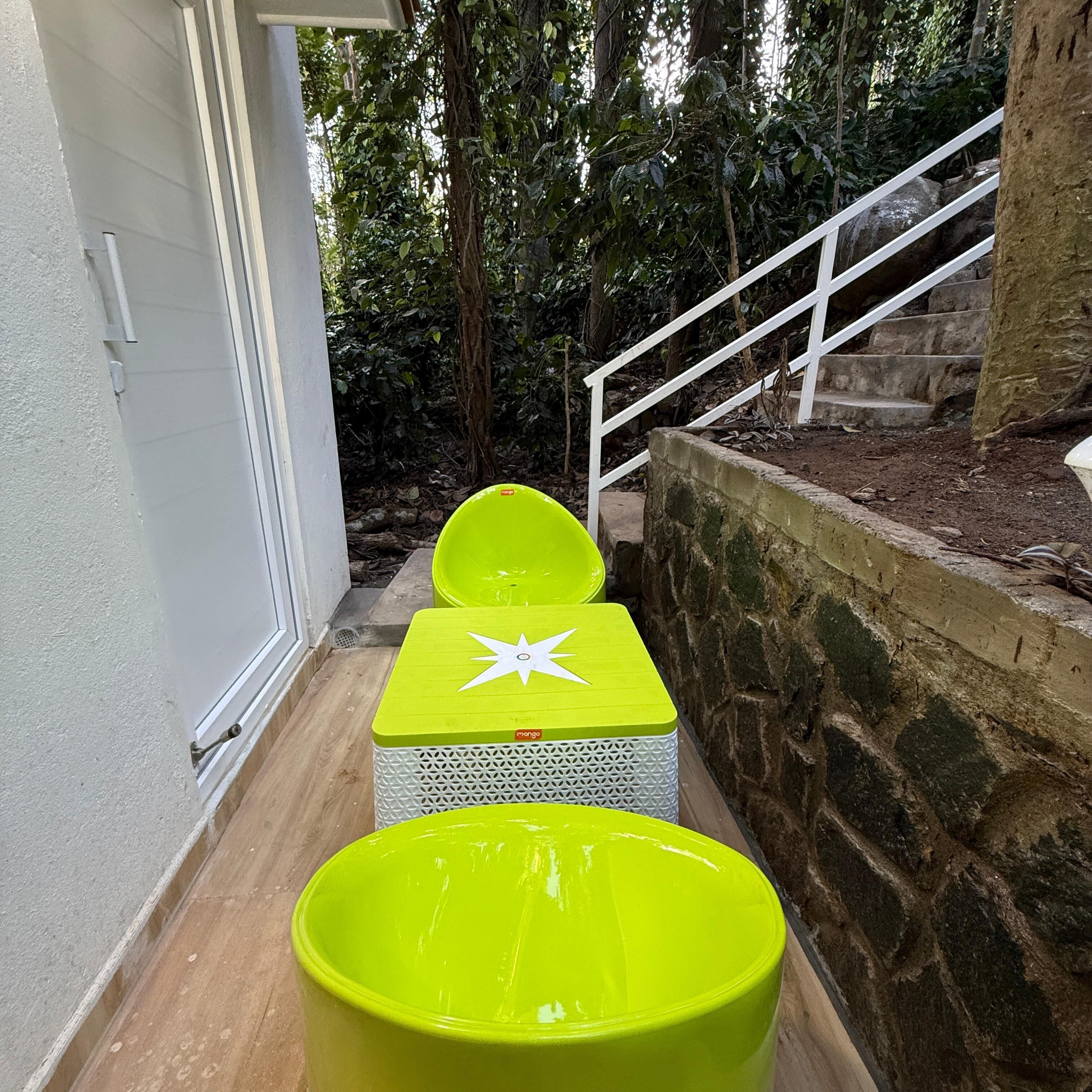 A set of bright green outdoor seating with a star design, located beside a stone wall and a white staircase.