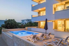 Um edifício moderno com piscina e cadeiras de descanso.