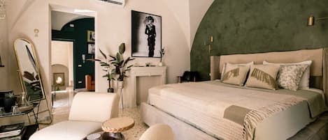 A spacious bedroom with a large bed, a sitting area with a round table, and a green accent wall.