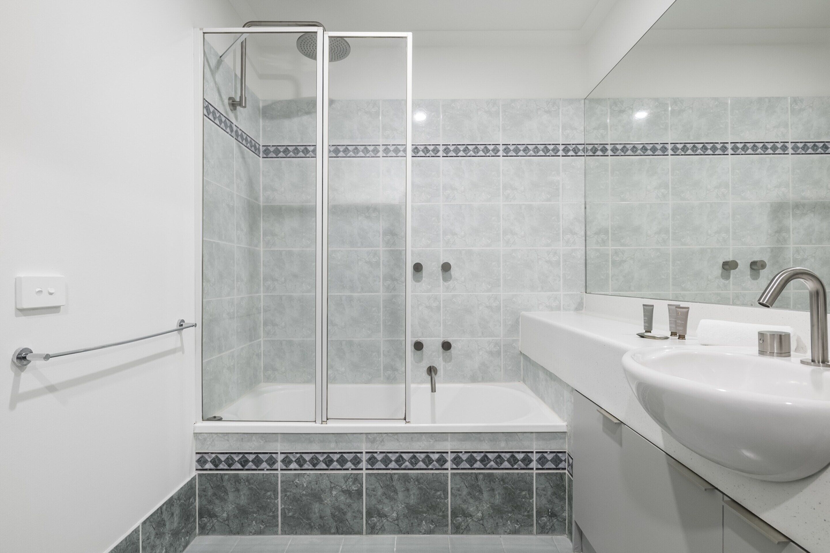 A modern bathroom with a glass-enclosed shower, a white sink, and a tiled backsplash.