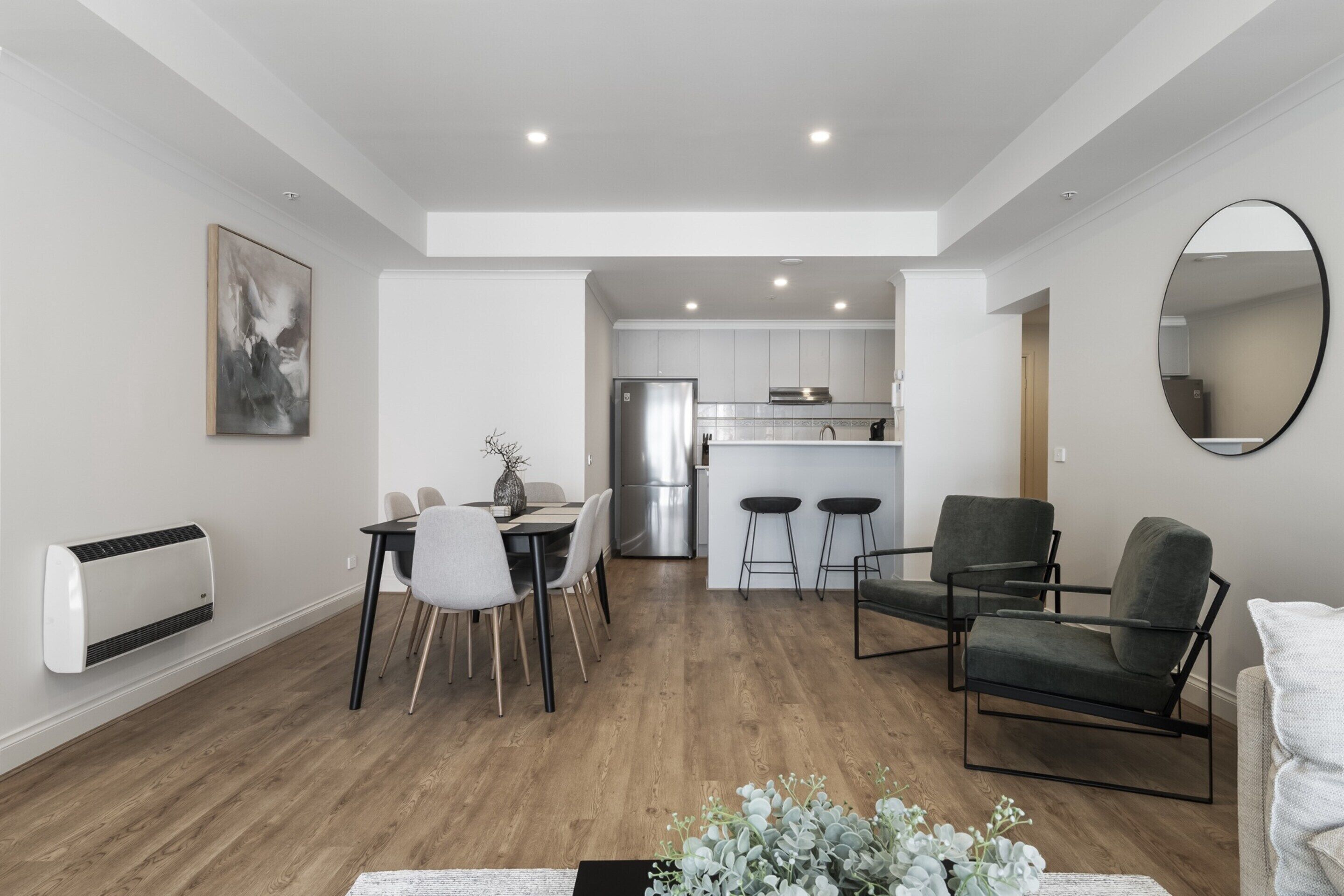 A modern apartment with a dining area, kitchen, and seating space.