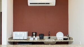 A kitchenette with a microwave, coffee maker, sink, and dish drying rack. - Pousada Caiçara Flats (Cabo Frio)