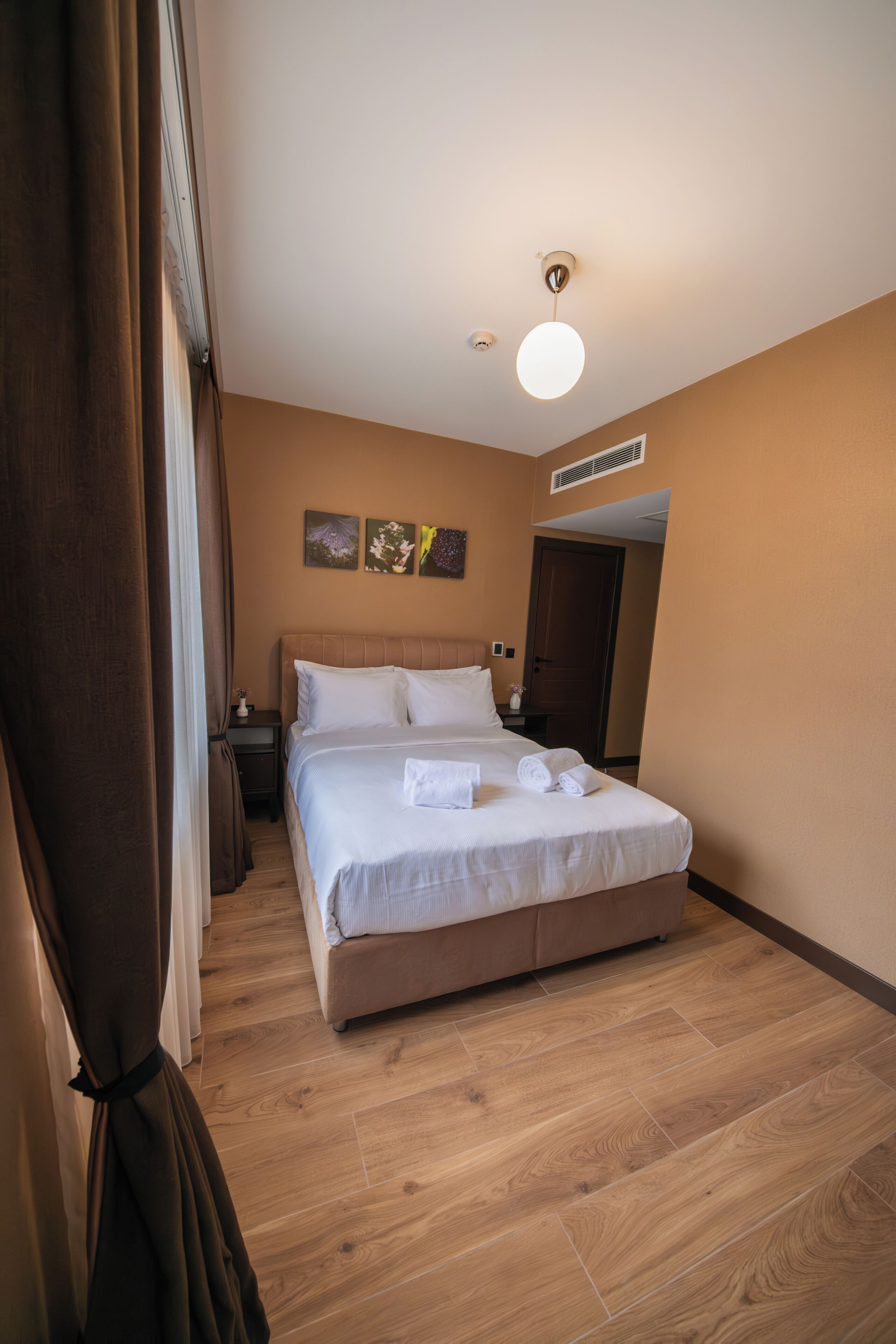 A hotel room with a large bed, a nightstand, a lamp, and a door.