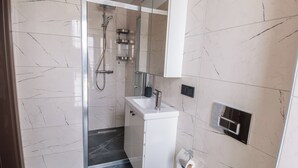 A modern bathroom with a toilet, sink, and shower. - Servi House (Akçaabat)