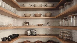 Een keuken met houten planken, een hanglamp en een betegelde achterwand.