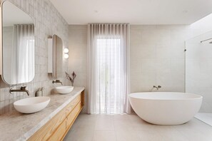 A modern bathroom with a large freestanding bathtub, two sinks with mirrors, and a shower area. - The Pavilion in Mount Martha (Melbourne)