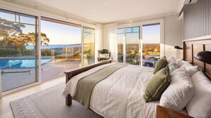 A bedroom with a large bed, a view of a swimming pool, and a cityscape through floor-to-ceiling windows. - Baymere Pool Spa City Views (Melbourne)