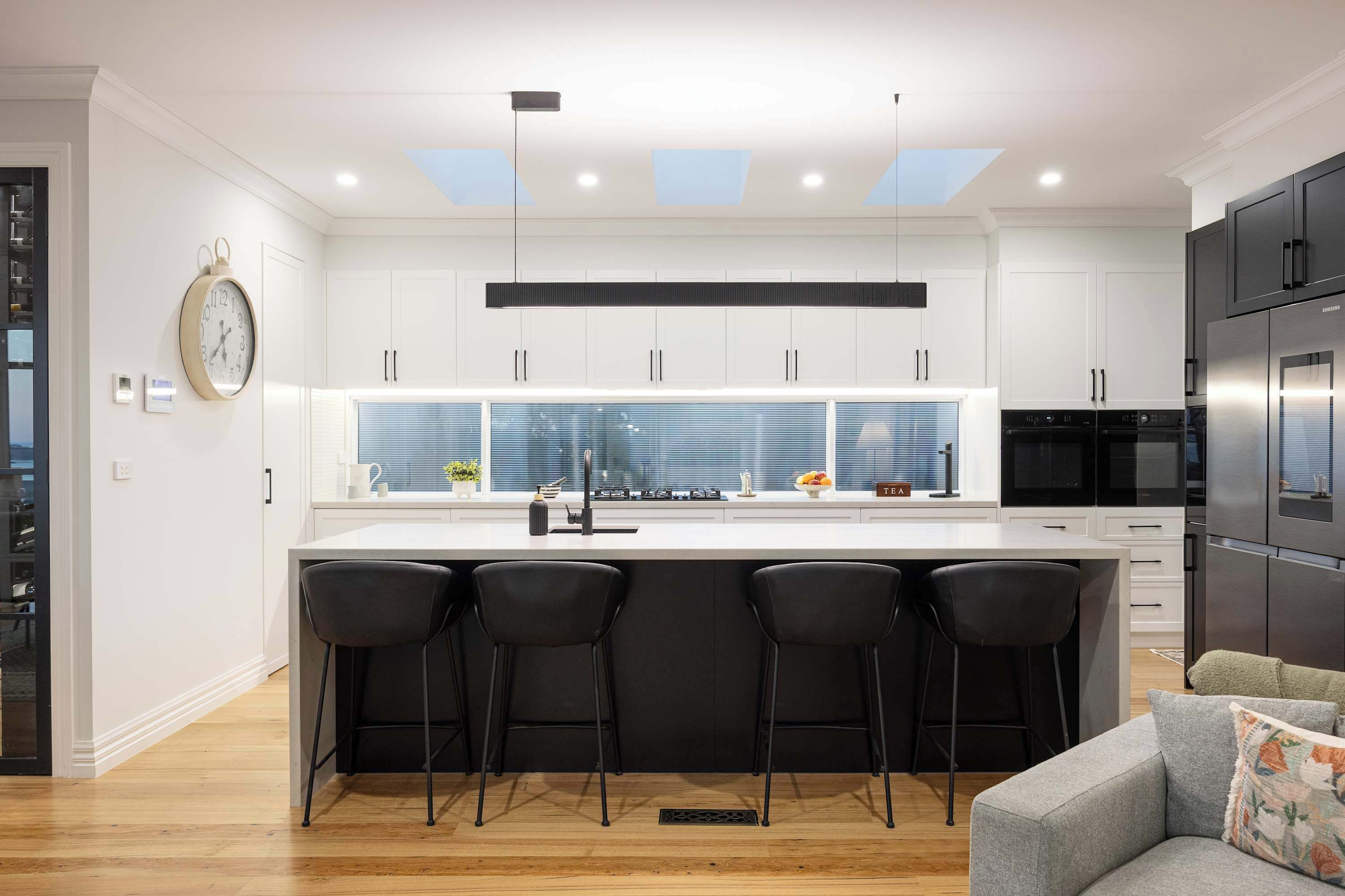 Una cocina moderna con una isla central, taburetes de bar y un horno empotrado.