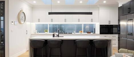 Una cocina moderna con una isla central, taburetes de bar y un horno empotrado.