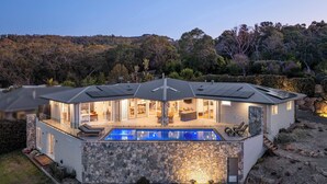 A modern house with a swimming pool, stone exterior, and a view of the surrounding forest. - Baymere Pool Spa City Views (Melbourne)