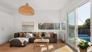Una sala moderna con un sofá modular, una mesa de centro y un ventanal con vistas a una piscina.