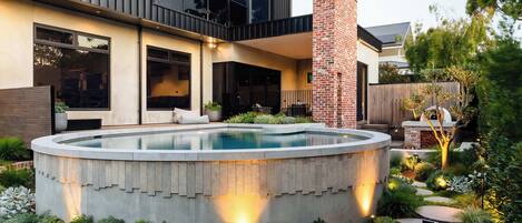 A modern house with a swimming pool, a brick chimney, and a well-maintained garden.