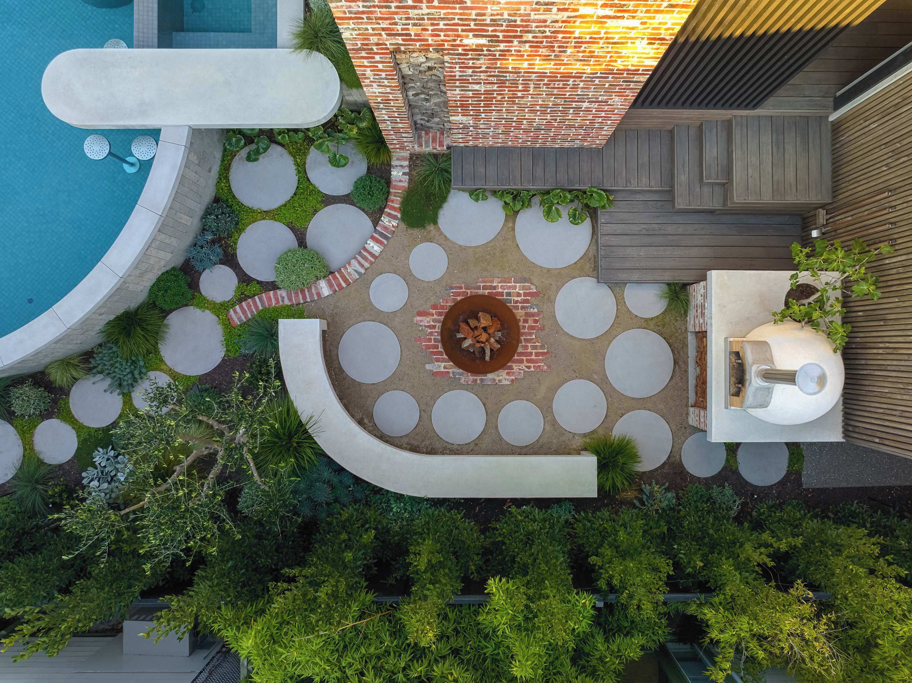 A rooftop garden with a swimming pool, circular seating areas, and a fire pit.