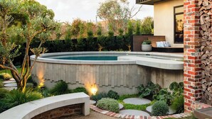 A modern outdoor patio with a fire pit, a swimming pool, and a brick wall. - Helix in Mornington With 4 Bedrooms and 3 5 Bathrooms (Melbourne)