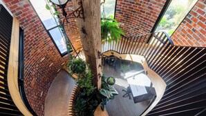 A spiral staircase with a brick wall and wooden railings, surrounded by potted plants and a view of greenery outside. - Helix in Mornington With 4 Bedrooms and 3 5 Bathrooms (Melbourne)