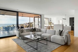 Uma sala de estar moderna com um amplo sofá de canto, uma mesa de centro e vista para a cidade.