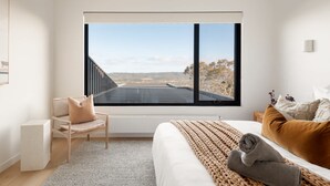 A bedroom with a large window, a bed, a chair, and a view of the landscape. - Banksia Luxury Home With Views (Melbourne)