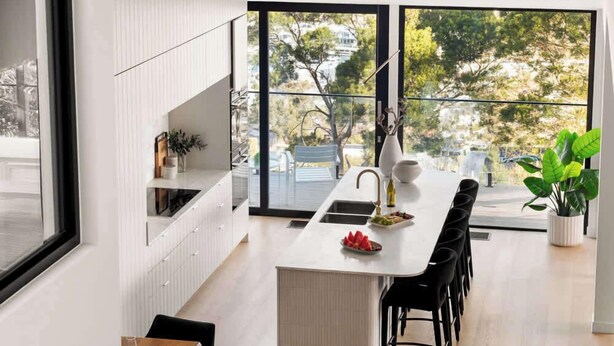 A modern kitchen with a central island, large windows, and a dining area with chairs. - Banksia Luxury Home With Views (Melbourne)