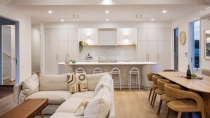 Une cuisine moderne avec des meubles blancs, un îlot central et des tabourets de bar.