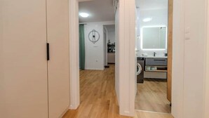 Un couloir menant à une salle de bain équipée d’un miroir et d’un lavabo.