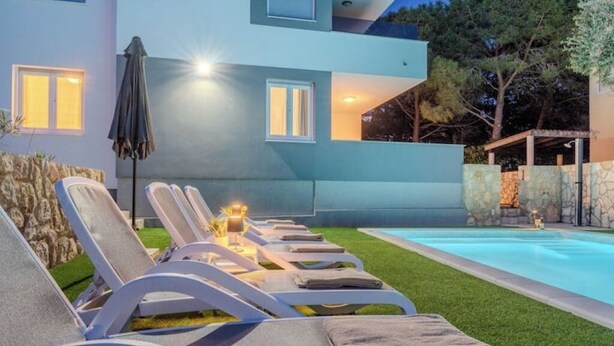 Un bâtiment moderne doté d’une piscine, de chaises longues et d’une pelouse bien entretenue.