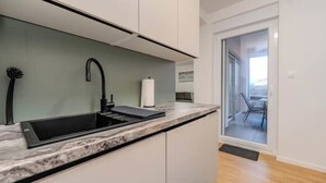 Une cuisine moderne avec un évier noir, des armoires blanches et un plan de travail en marbre.