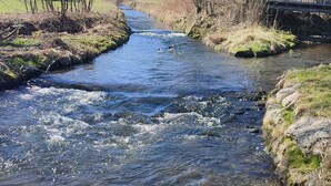A clear river flowing through a rural landscape with trees and a bridge in the background. - Holly-WOOD Allgäu vacation apartment - relaxation with heart in the countryside (Markt Rettenbach)